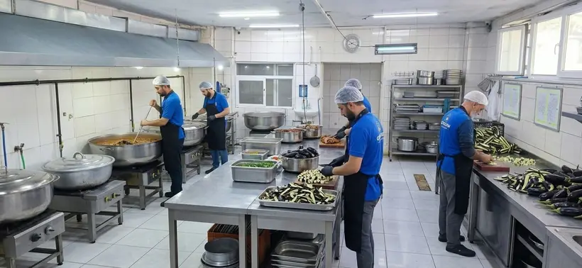 Göksan mutfağında ustalar kazanlarda yemek pişirip sebze hazırlıyor